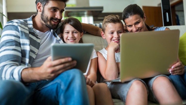 Family sitting on the sofa with tablets in hand