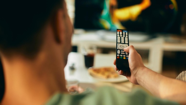 A man holding a remote control about to watch TV