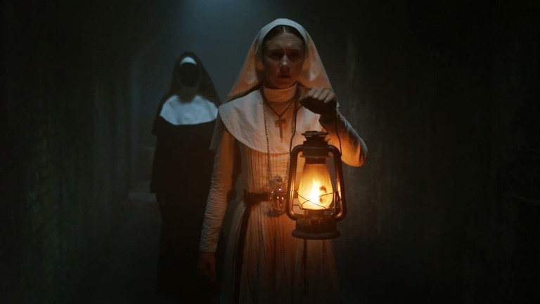 Two nun in darkness holding a lamp