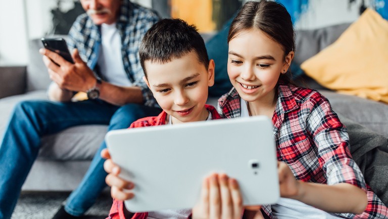 Two kids sitting holding a tablet