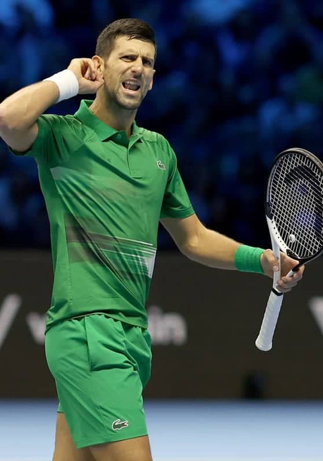Man dressed in green holding a tennis racket