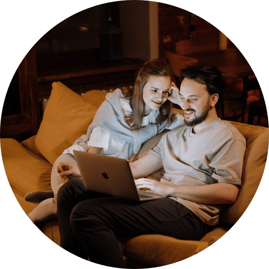 Happy couple sitting on the sofa in front of a laptop