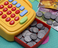 A toy cash register with coins inside of it