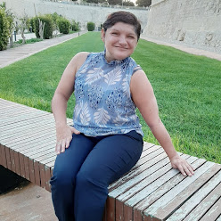 A woman sitting on a bench outside posing for a photo