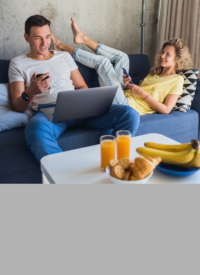 Young couple sitting on the sofa with devices in hand