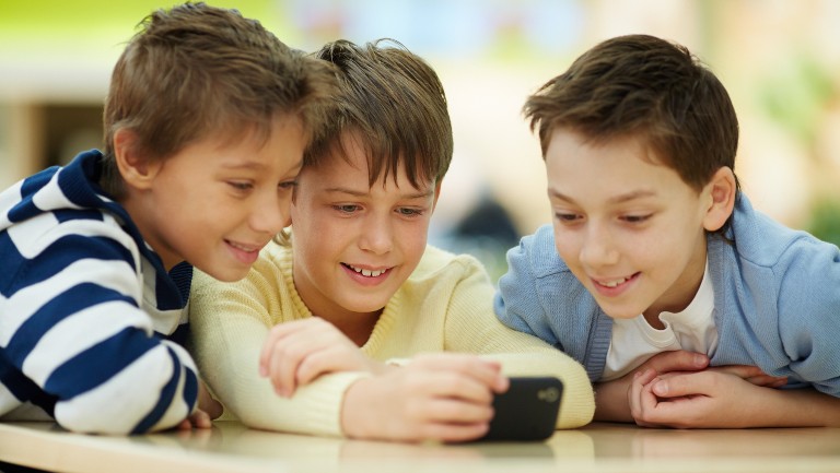 Three boys looking at a mobile phone